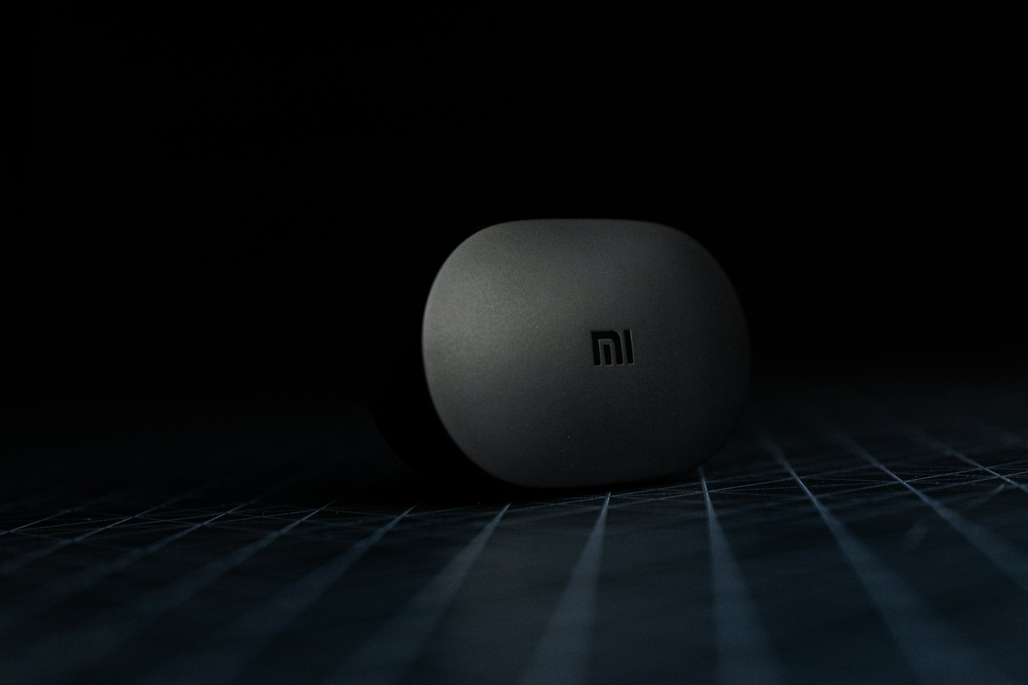 A sleek rounded electronic device rests on a grid surface.
